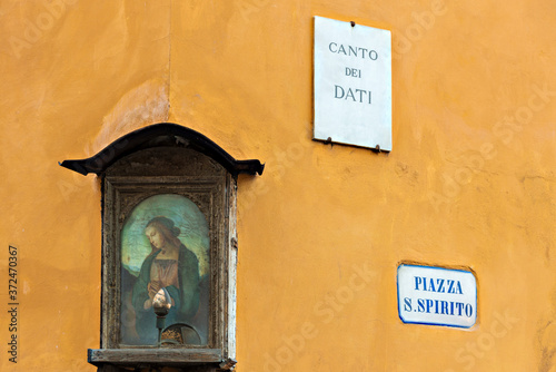a poetic glimpse on piazza Santo Spirito heart of the popular San Frediano district of Florence with a small tabernacle in the foreground