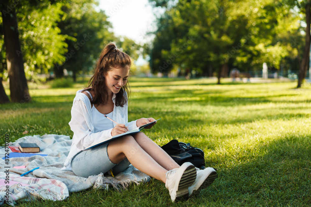 Smiling young girl studying in park Smiling young girl studying in park