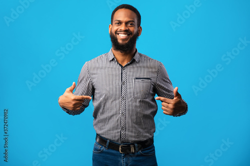 Happy young man pointing fingers at himself photo