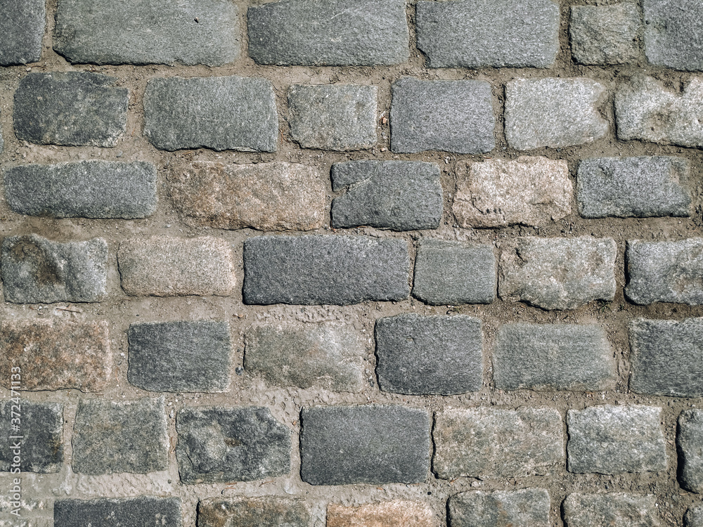 An old dark gray paving stone pavement. Road texture. An old dark gray paving stone pavement. Road texture.
