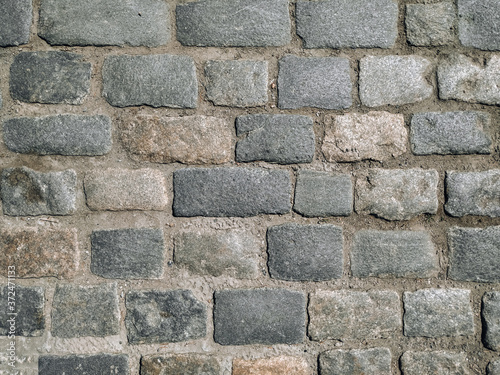 An old dark gray paving stone pavement. Road texture.