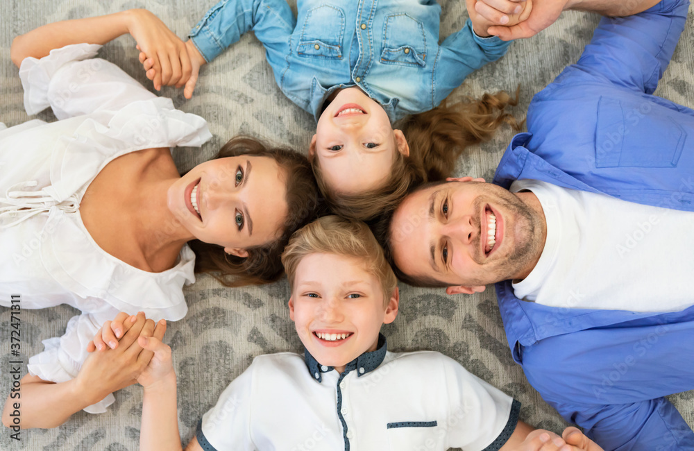 Family Lying Holding Hands Smiling Posing On Floor Indoors, Above-View
