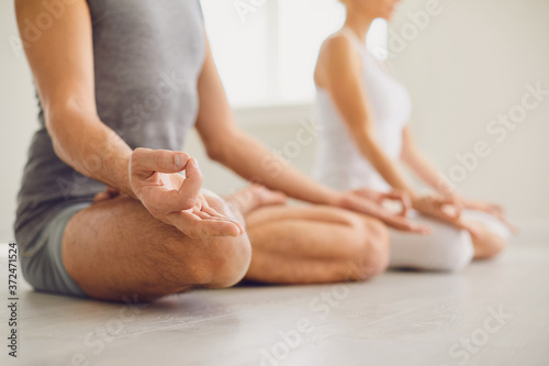 Calm couple meditates relax in lotus position in yoga class.