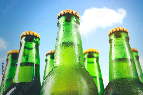 Close up of five cold beer bottles under blue sky photo