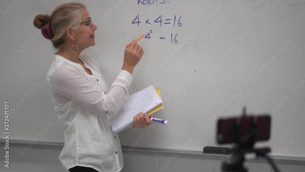 Motion view of woman teacher giving a virtual online math class online to students using smartphone during a pandemic. Motion view of woman teacher giving a virtual online math class online to students using smartphone during a pandemic.