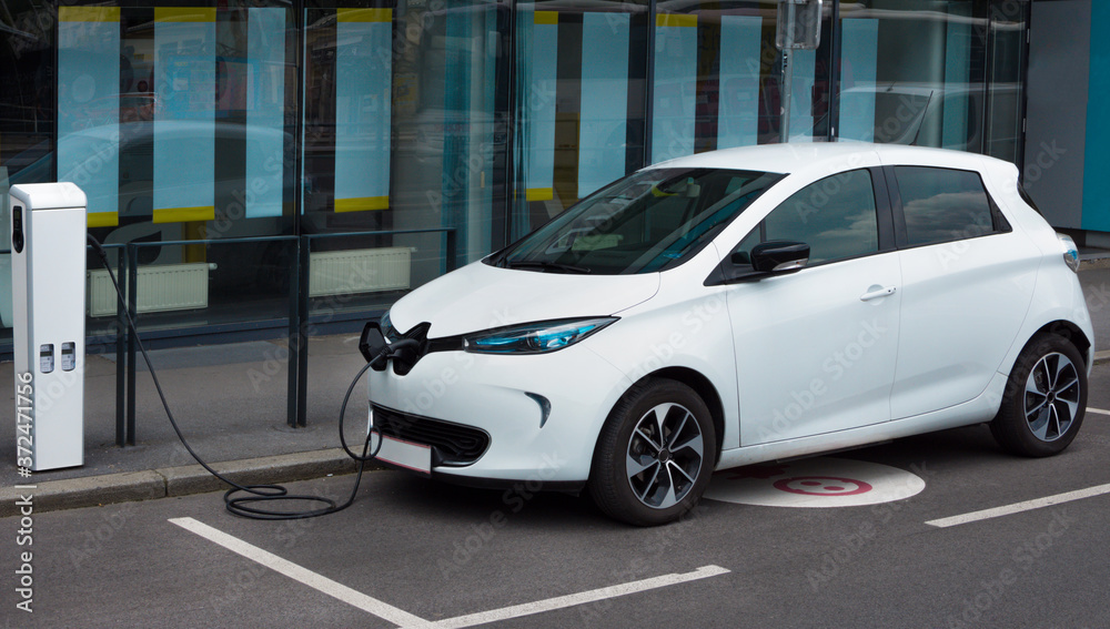 Modern electric car plugged in charging on the street station. New energy vehicles, environment friendly alternative energy for cars