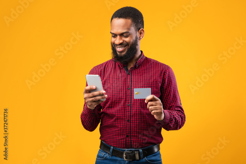 Black male holding credit card and cellphone at studio