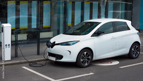 Obraz na płótnie Modern electric car plugged in charging on the street station. New energy vehicles, environment friendly alternative energy for cars w salonie