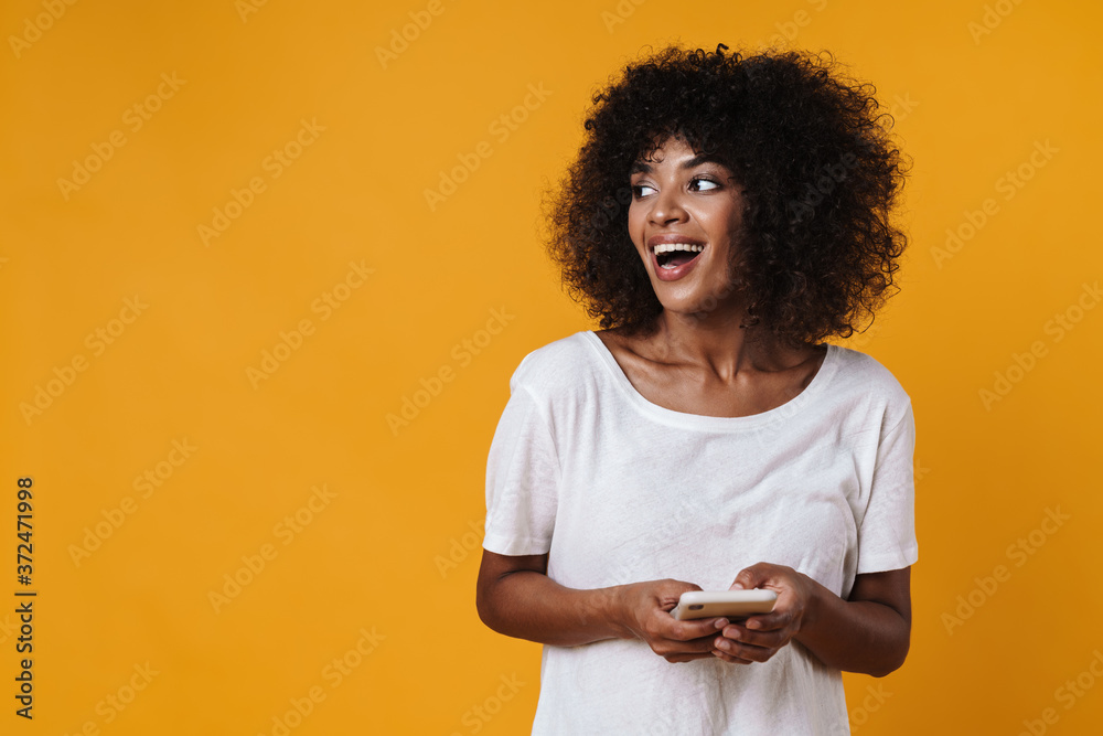 Image of happy african american girl smiling and using mobile phone Image of happy african american girl smiling and using mobile phone
