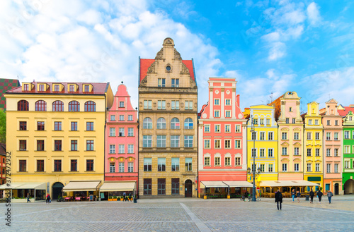 Row of colorful traditional buildings with multicolored facades on cobblestone Rynek Market Square in old town historical city centre of Wroclaw, blue sky background, Poland