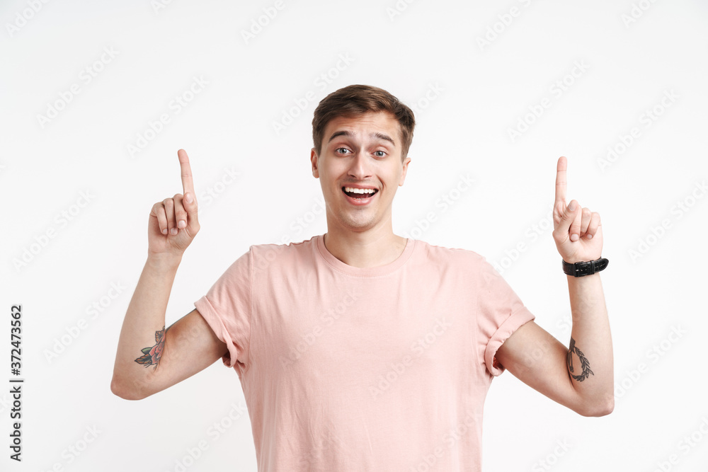 Image of cheerful caucasian man in basic t-shirt smiling and pointing fingers up Image of cheerful caucasian man in basic t-shirt smiling and pointing fingers up