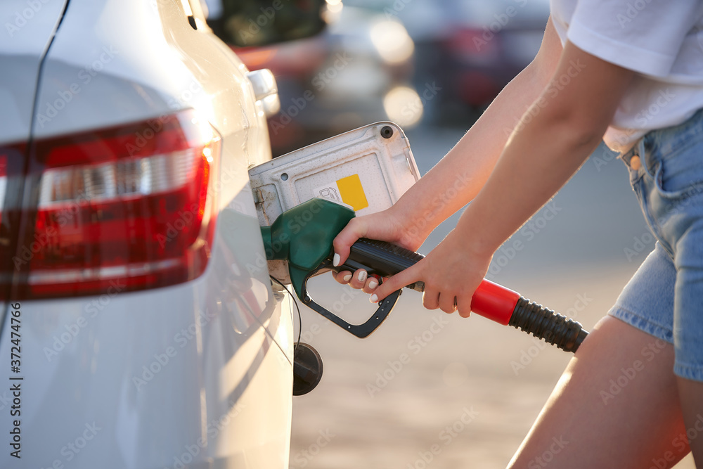 Handle fuel nozzle to refuel. Female hands hold a refueling nozzle
