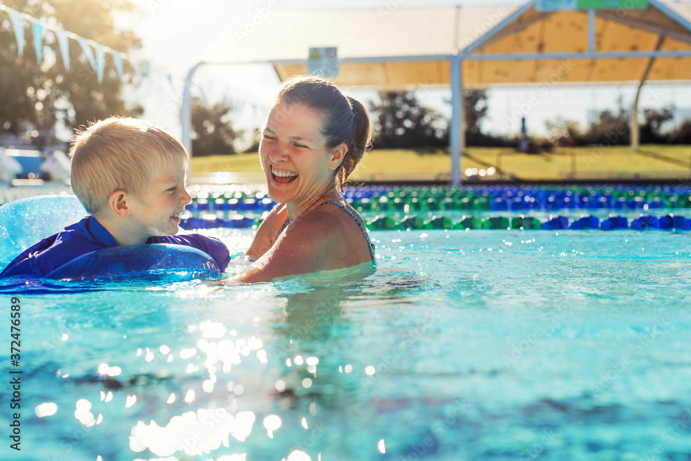 Mother and little boy in swimming pool outside in sunny day, smiling face, enjoy in the water, close up portrait.