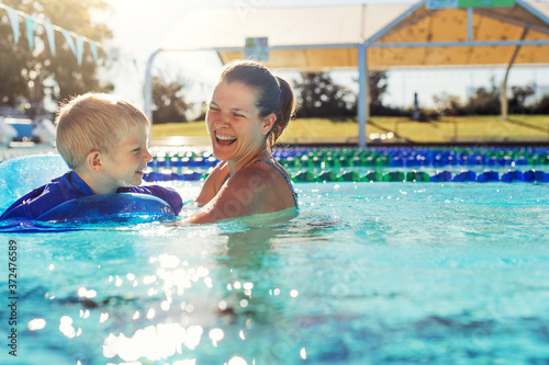 Mother and little boy in swimming pool outside in sunny day, smiling face, enjoy in the water, close up portrait.