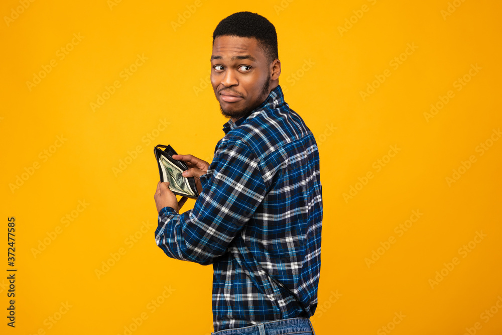 Sneaky Black Man Holding Wallet With Money On Yellow Background Sneaky Black Man Holding Wallet With Money On Yellow Background