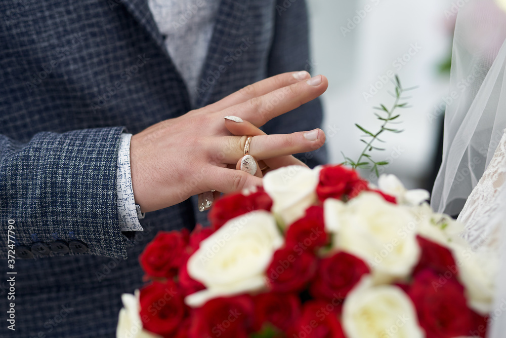 The bride gently and with trepidation puts a gold ring on the groom's finger close-up The bride gently and with trepidation puts a gold ring on the groom's finger close-up