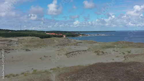 Drone flight over white sand dunes with city of Nida in distance photo