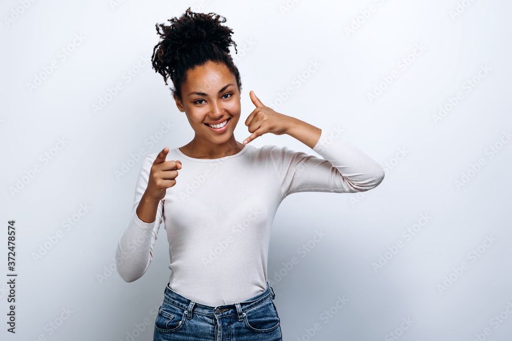 Positive curly girl in casual clothes shows thumb in camera and gesture Positive curly girl in casual clothes shows thumb in camera and gesture