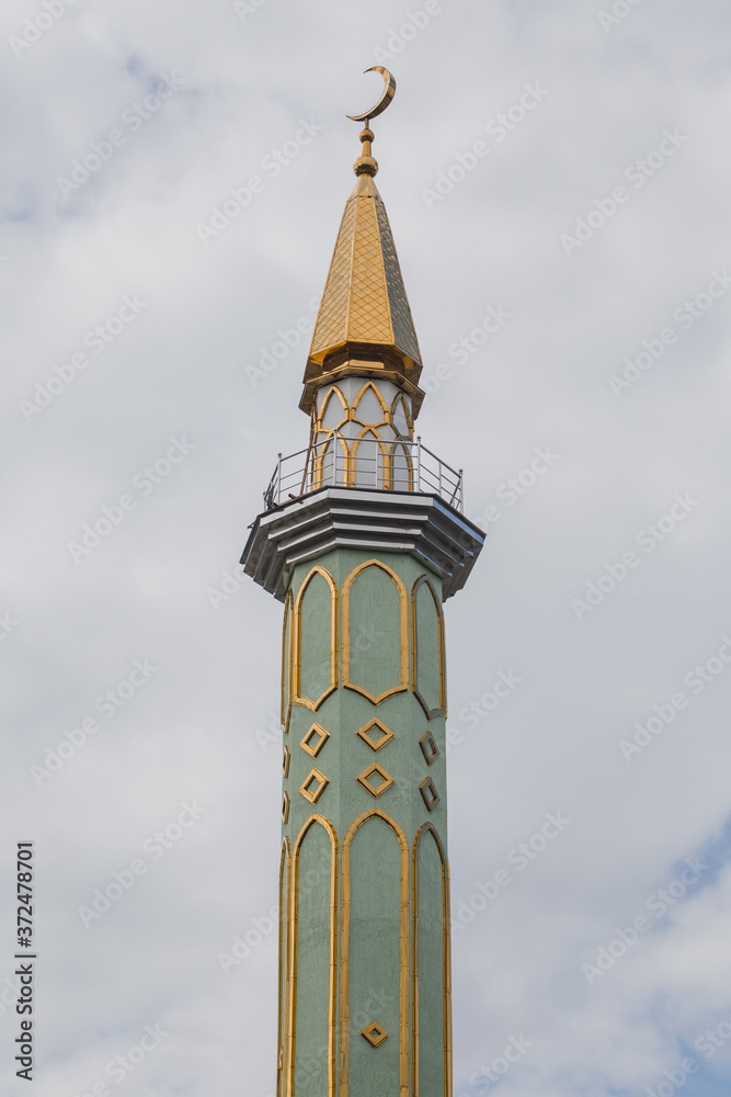 View of traditional mosque minaret tower, distinctive architectural feature of mosques. Traditional and typical mosque architectural details.