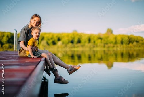 Cool kid boy with mother sitting on dock. Summer photography for a blog or advertising about family and travel photo