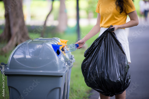 Asian women are collecting plastic waste in trash cans to keep it clean.