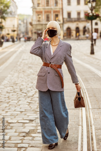 Bilde på lerret Street style during quarantine: woman wearing protective face mask, trendy autum