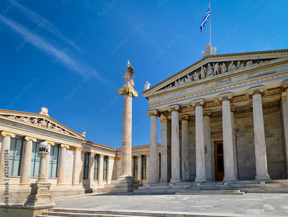Entrance to Academy of Athens, Greece, and column with statue of Athena, ancient Greek goddess, patron of city, in bright daylight, summer sunshine.