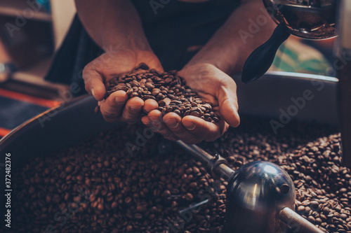 Man holding freshly roasted coffee beans in his hands.