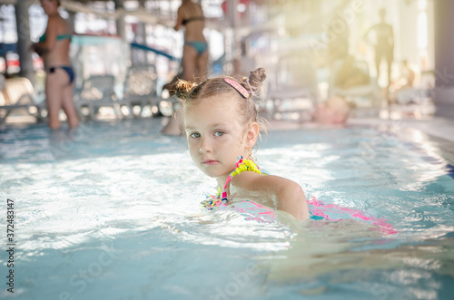 little beautiful girl playing with a foam noodle in a indoor pool. rest in the water park   © silentalex88