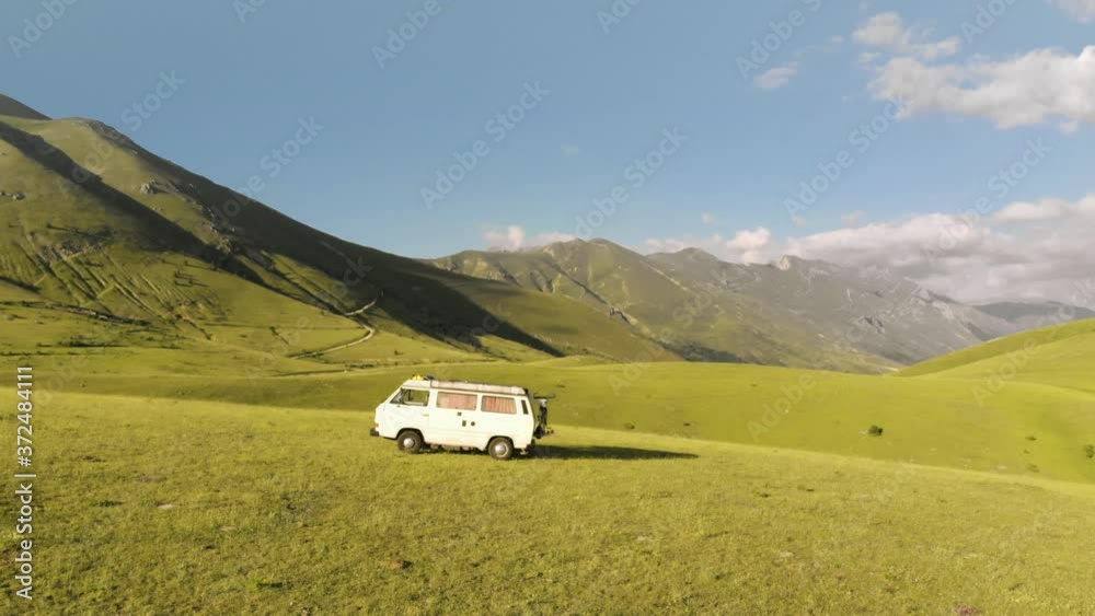 Aerial view of a traveler van in a green prairie. 4k