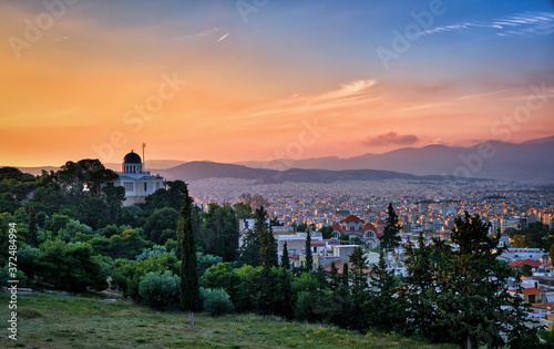View of Athens, Greece and residential areas from Pnyx hill in soft sunlight and great sunset sky. National observatory of Athens in foreground.
