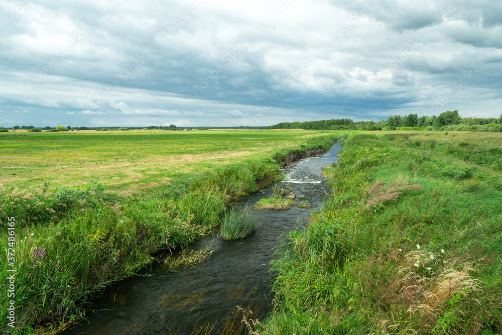 The small river Uherka in eastern Poland flowing through meadows