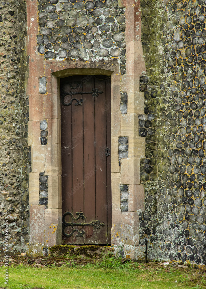 An very old oak side door in a old flint wall to an english church in summer