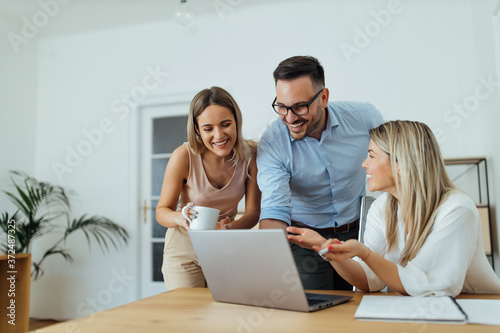 Portrait of a happy business team looking at laptop.