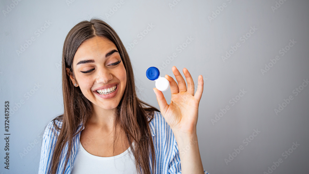 Happy Woman Holding Contact Lenses Case. Woman with Contact Lenses Case in Optical Store - Beautiful girl holding contact lens container in optician shop Happy Woman Holding Contact Lenses Case. Woman with Contact Lenses Case in Optical Store - Beautiful girl holding contact lens container in optician shop
