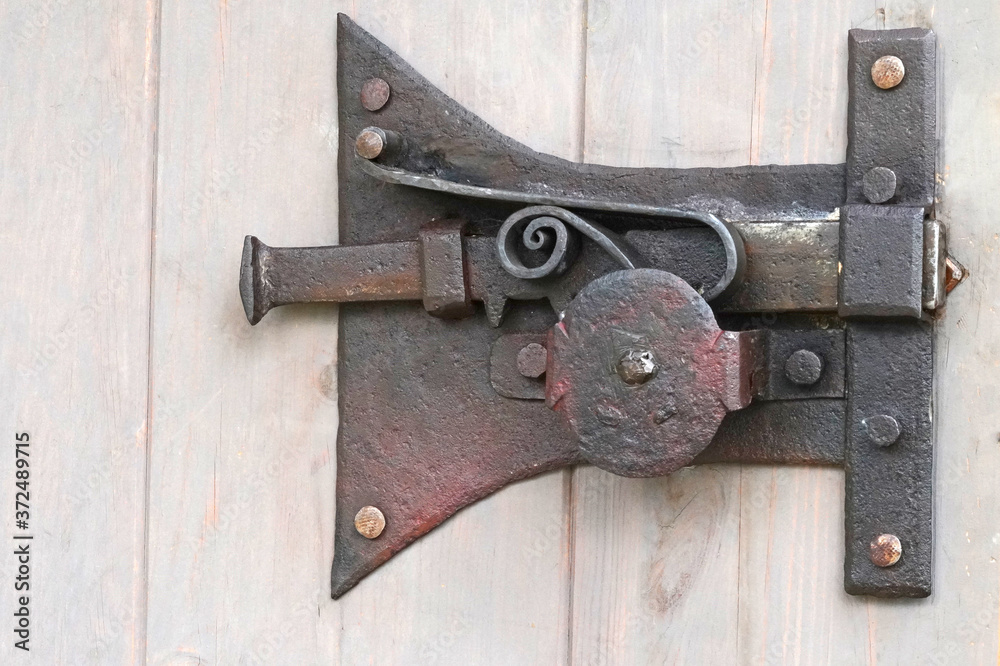 Close-up shot of a ancient iron latch on a wooden door Close-up shot of a ancient iron latch on a wooden door