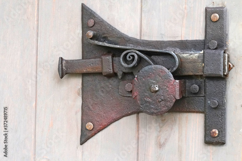 Close-up shot of a ancient iron latch on a wooden door