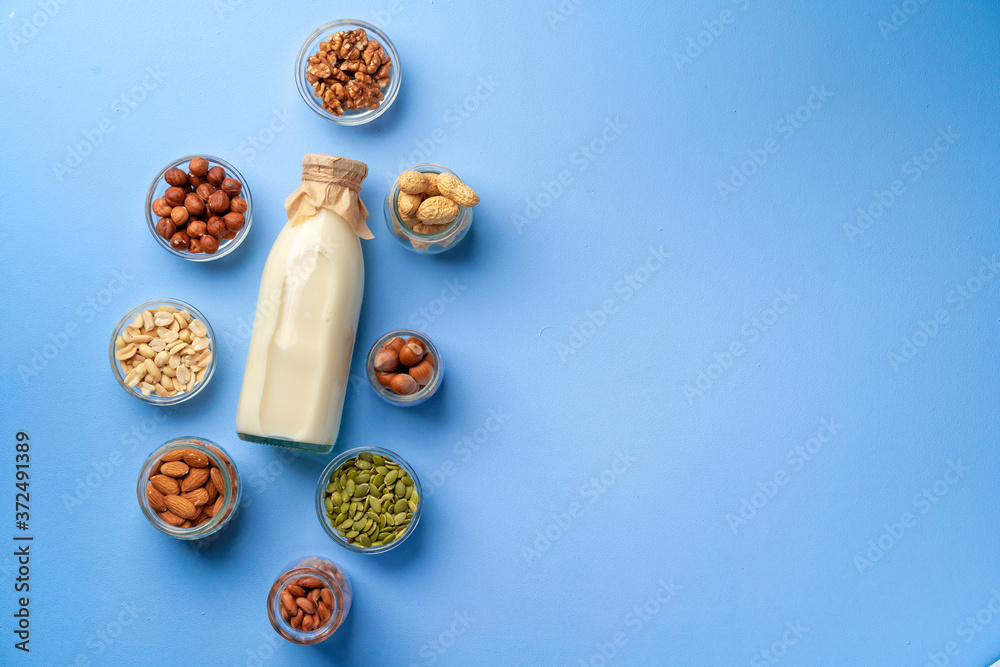 Vegetable milk concept with milk bottle and bowls with grains on blue background top view Vegetable milk concept with milk bottle and bowls with grains on blue background top view