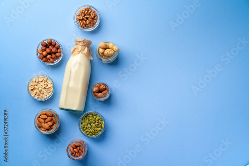Vegetable milk concept with milk bottle and bowls with grains on blue background top view