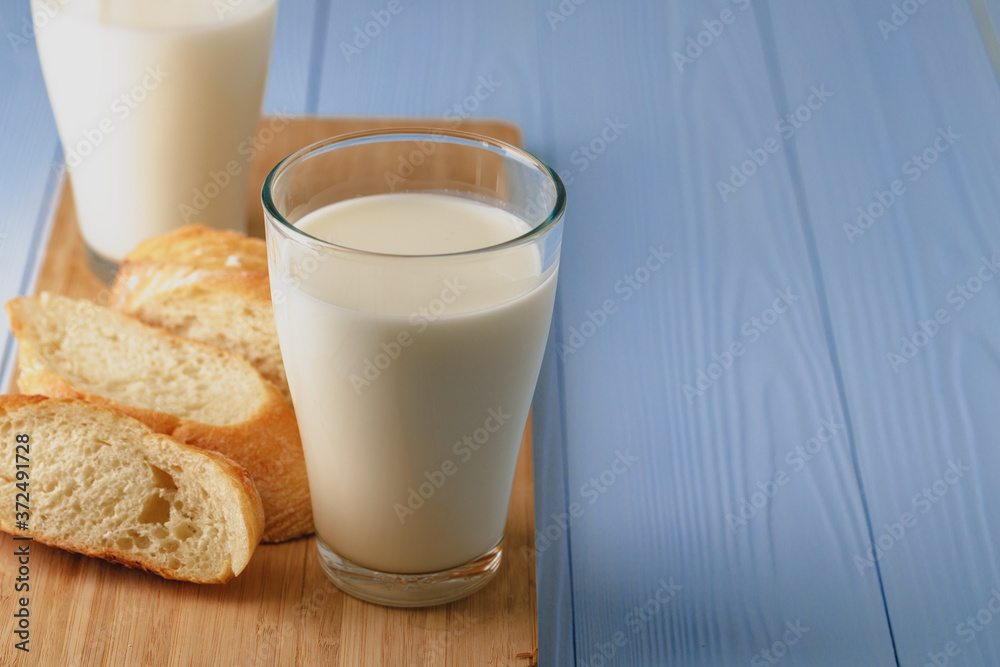 Glass of milk with sliced baguette on wooden board Glass of milk with sliced baguette on wooden board