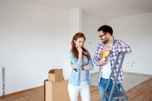 Couple in new house plan how to paint walls and looking at samples of colours with brushes on hand © pucko_ns