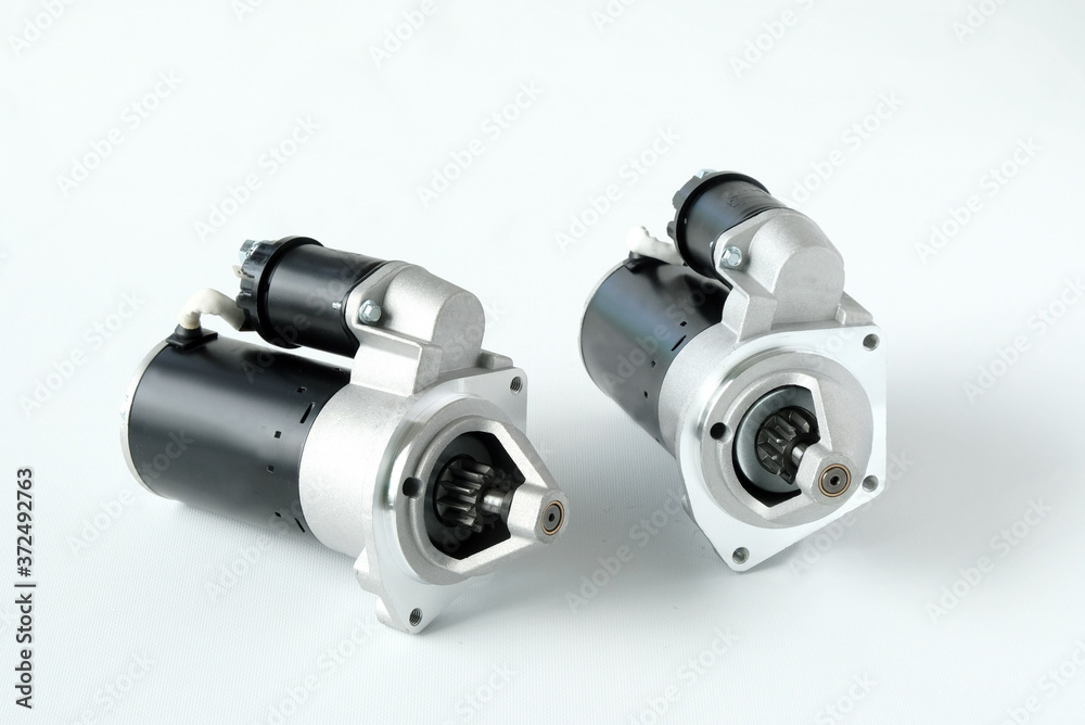 Spare parts for passenger cars. Close-up of two new car starters on a white background, top view. Spare parts for passenger cars. Close-up of two new car starters on a white background, top view.
