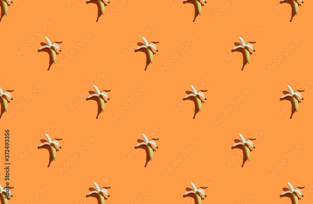 Trendy sunlight Summer pattern made with banana on bright light orange background Trendy sunlight Summer pattern made with banana on bright light orange background