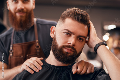 Bearded man checking haircut near barber