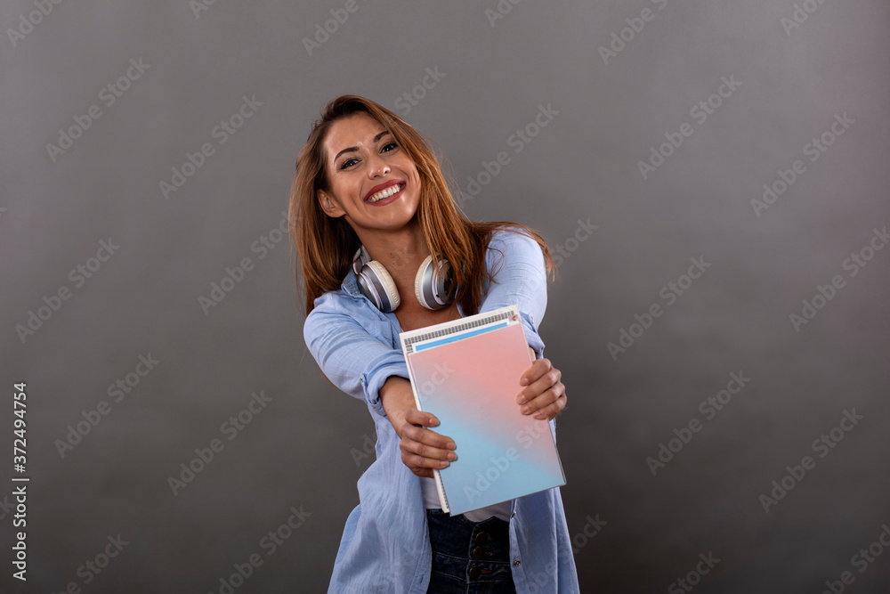 Student girl with books on hand and headphones over her neck smile Student girl with books on hand and headphones over her neck smile