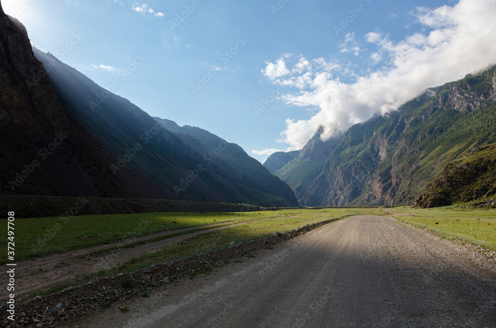 a canyon with a dirt road among the fjords. a ray of light illuminates a gorge in a beautiful mountain valley.