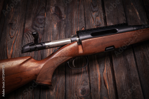 Rifle with a wooden stock on a dark back. Weapons for sports, hunting and self-defense.