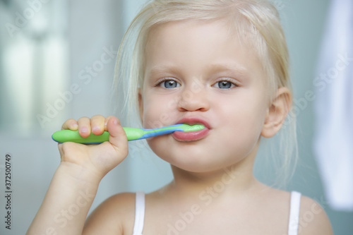 Adorable 3 years old girl brushing her teeth in bathroom. 