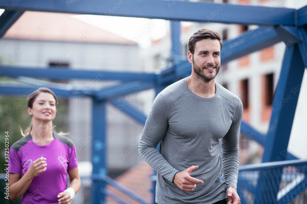 Athletic couple jogging in the city. Happy couple training outdoors. Athletic couple jogging in the city. Happy couple training outdoors.