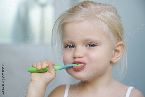 Adorable 3 years old girl brushing her teeth in bathroom. 